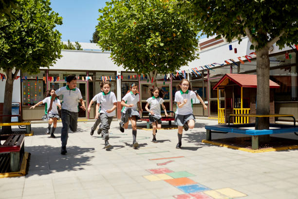 giovani ragazzi e ragazze che corrono attraverso il cortile della scuola - elementary school building foto e immagini stock
