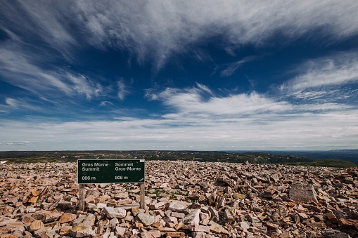 A shot of the sign with road information in the brown rocks under the blue sky.