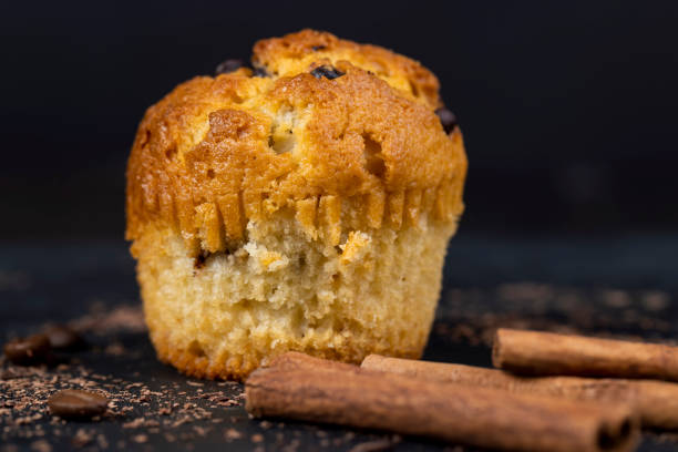 Close-up on baked muffin in wax paper cup, served on grid