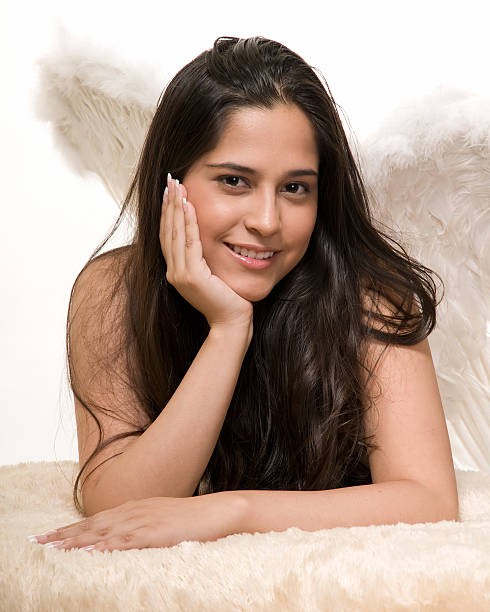 close up of an attractive pretty brunette woman wearing angel wings leaning on hand up close over white