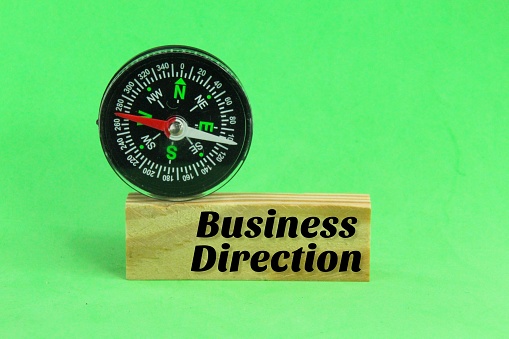 compass and wooden board with the word business direction. business strategy concept