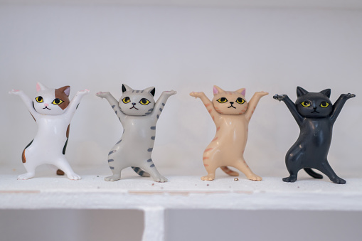 A row of cute funny cat figurines on a white self