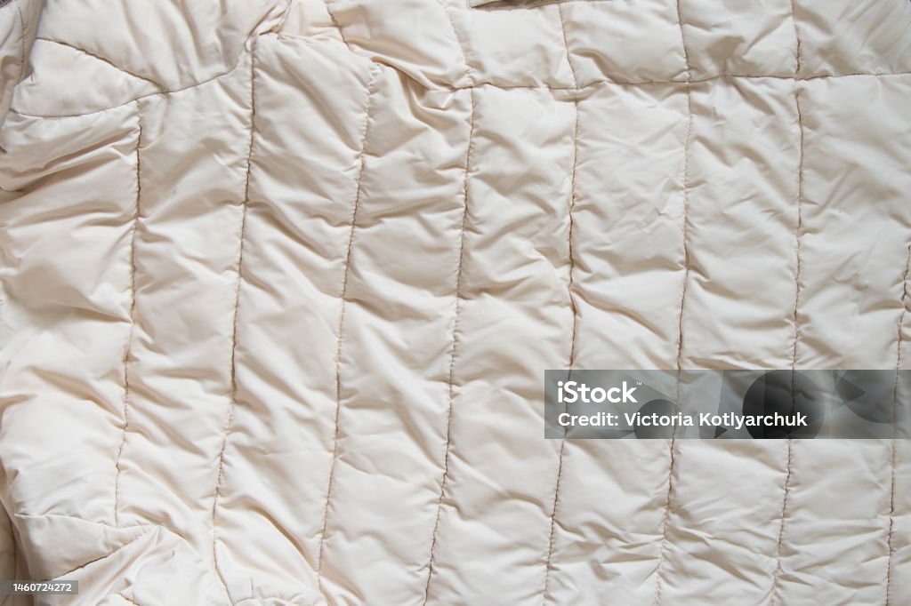 women's padded white soft jacket as background, of soft light fabric women's padded white soft jacket as background, background of soft light fabric Padded Jacket Stock Photo