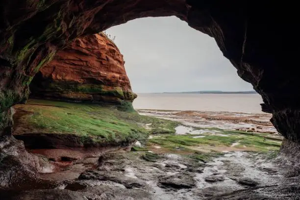 Photo of Natural arch and cliffs before a sea in Nova Scotia, Canada on a clouded day