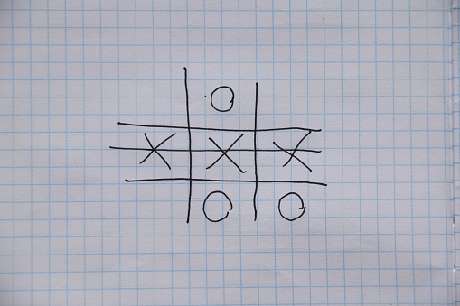 the game of tic-tac-toe is drawn with a pen on a crumpled notebook in a cage, play and rest, children's game of tic-tac-toe