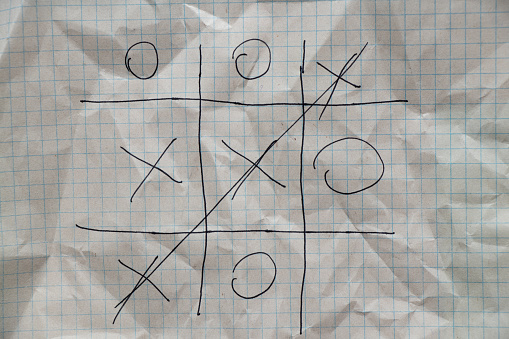the game of tic-tac-toe is drawn with a pen on a crumpled notebook in a cage, play and rest, children's game of tic-tac-toe