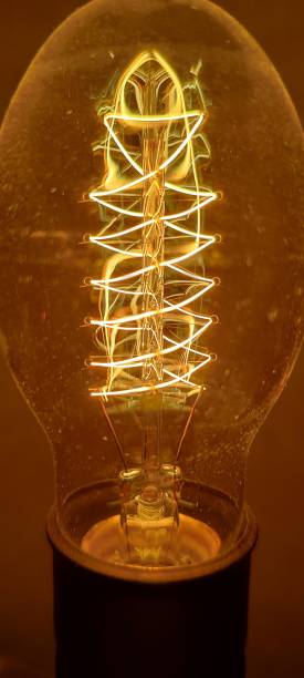 istock Vertical shot of an illuminated vintage bulb with yellow light 1460725224