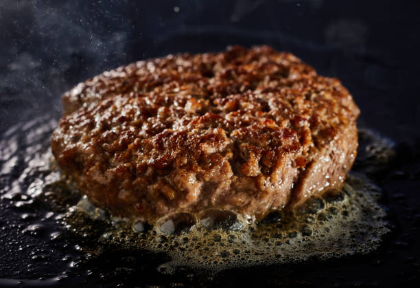 istock Thick juicy minced beef patty for a traditional burger grilling on a griddle 1460725439