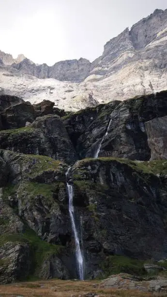 A vertical shot of a waterwall falling from the mountains with high cliffs in the background