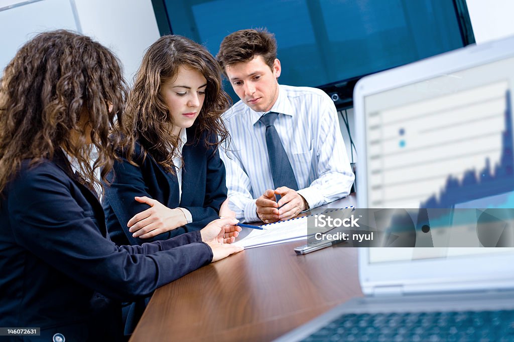 Business teamwork Happy young businesspeople having meeting in board room. Graph showing progress on laptop screen. Click here for other business images: 25-29 Years Stock Photo