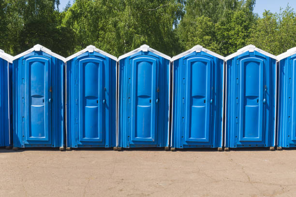 istock Blue plastic biodegradable toilet stalls line up in an outdoor activity area. 1460726933