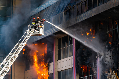 A closeup of Firefighters on the stairs extinguish a big fire