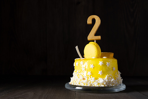 The number Two on a yellow cake for an anniversary or birthday in a dark key