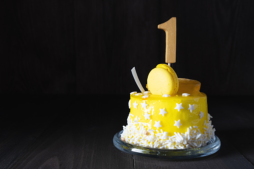 The number One on a yellow cake for an anniversary or birthday in a dark key
