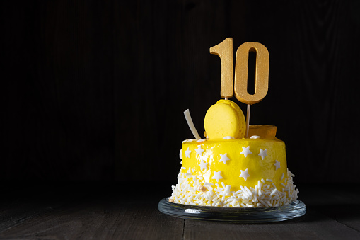 The number Ten on a yellow cake for an anniversary or birthday in a dark key.