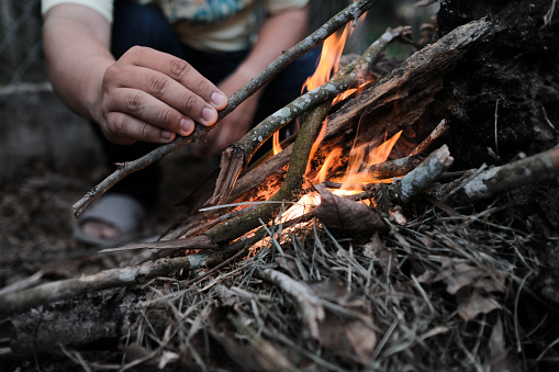 A closeup shot of a male hand making a fire in the forest