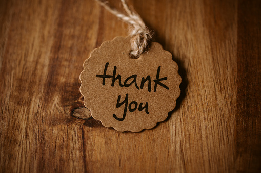 Thank you word written in a card on wooden background with selective focus. Love and gratitude concept.