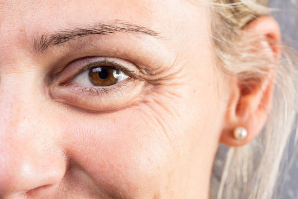 Wrinkled eye with crow's feet of beautiful lady Macro of the eye of a smiling woman showing signs of age such as crow's feet and wrinkles wrinkled stock pictures, royalty-free photos & images