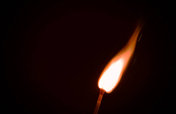 istock Closeup shot of a burning match on a black background 1460732255