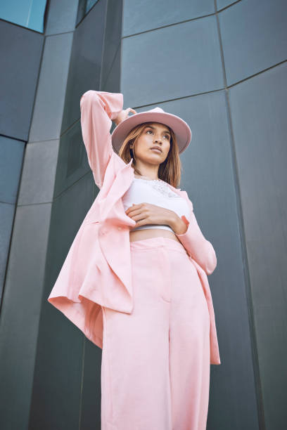 istock Fashionable young hispanic model wearing a stylish trendy pink suit and hat while posing outside against a modern building in the city 1460732831