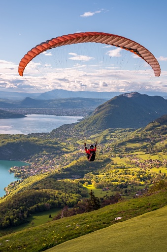 A vertical of an extreme sports lover paragliding in a picturesque landscape surrounding lake Annecy