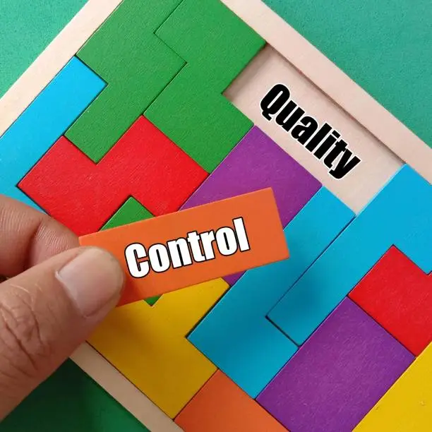 Photo of Business Teamwork Concept- Hand holding orange wooden puzzle with text CONTROL and QUALITY