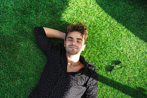 A young attractive man lying on artificial grass and relaxing