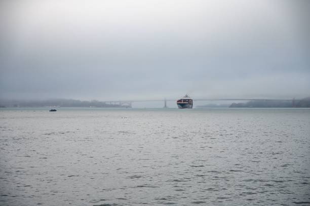 vista frontal de grande navio de carga de contêineres entrando no porto de são francisco através da ponte e neblina - port of san francisco - fotografias e filmes do acervo