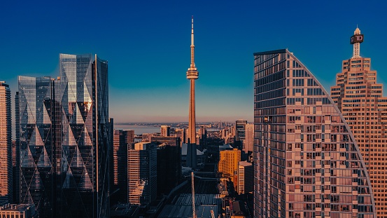 September 2023- Toronto, Canada: View on the Canadian National - CN - Tower (communications tower), taken from downtown Toronto by Union Station, with beautiful skies shortly after rain and the beginning of sunset and an airplane flying over.