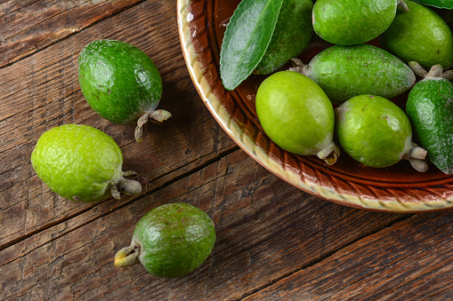 A top view of Feijoa fruits on a plate on a wooden table