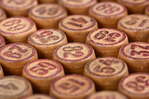 A selective focus shot of the rows of the wooden barrels of vintage lotto board game