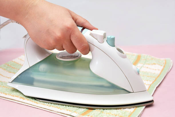 istock Female hand ironing clothes on a gray background 1460743719