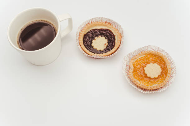 isolated apricot and cherry jam tart in a paper backing cup and cup of coffee on a white background with text space