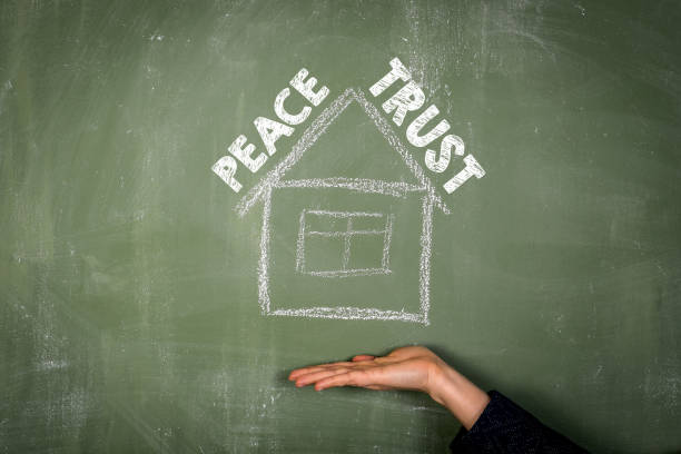 istock Peace and Trust concept. Text and house on green chalkboard 1460744228