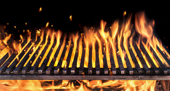 Barbecue grill with fire flames closeup on dark background.