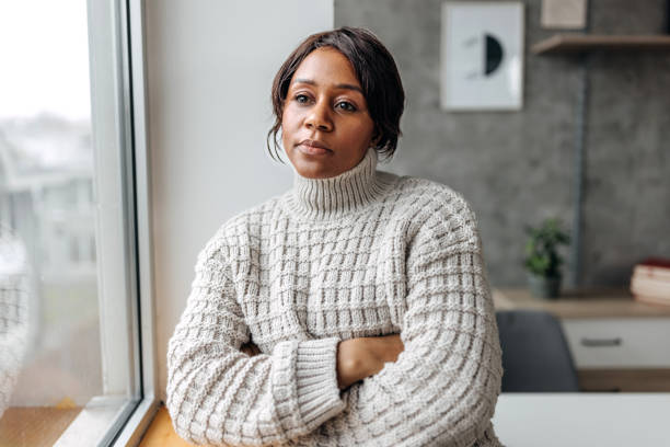istock Young beautiful woman contemplating her thoughts while looking through window at her apartment 1460746870