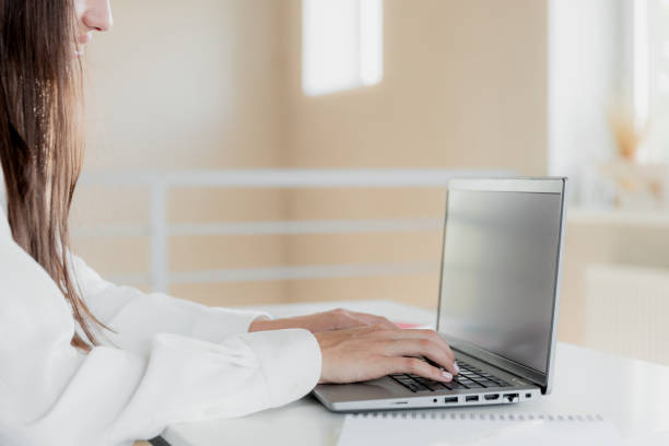 istock Woman hands typing on the laptop with blank white screen mockup laying on table 1460747024