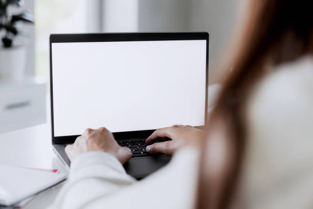 istock Woman hands typing on the laptop with blank white screen mockup laying on table 1460747043