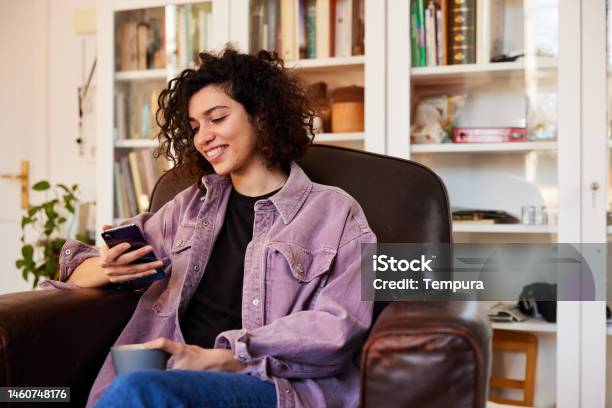 Homebound Woman Using Phone In A Living Room Stock Photo - Download Image Now - 30-34 Years, Adult, Adults Only
