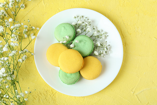 Concept of tasty dessert with macaroons on yellow background