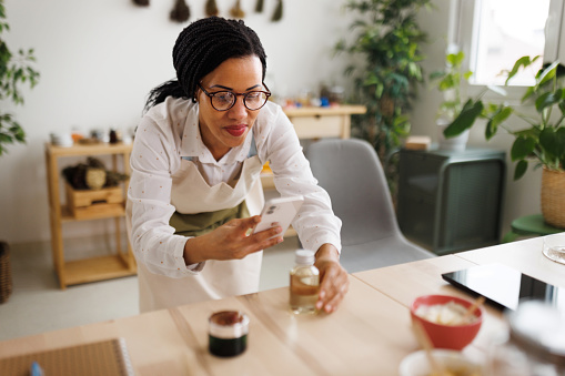 Woman photographing her self made skin care oil that she made for her small business