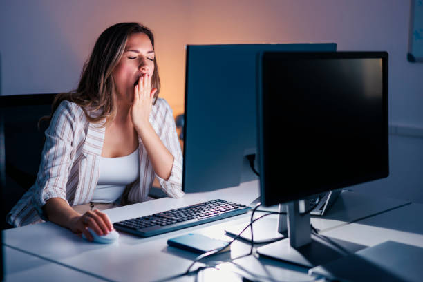 istock Woman yawning at her desk while working late at night 1460756172