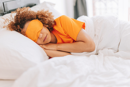 african american lady wearing sleeping mask lying peacefully under the bed sheet - sweet dreams
