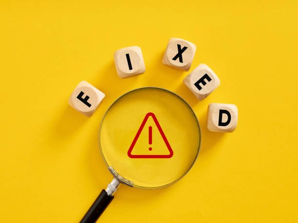 istock To fix an error or system bug. The word fixed on wooden cubes with a magnifier on a warning symbol. 1460761788