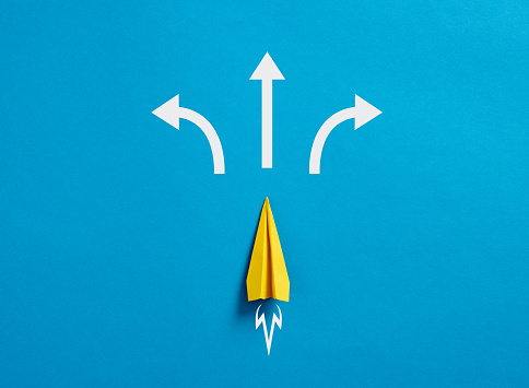 Business decision making and the way to success. Choosing a strategic path to move forward. Alternative options and business solutions. Paper plane with arrows pointing different directions.