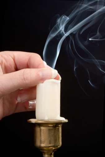 Female hand extinguishing the flame of a candle