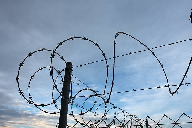 istock Razor wire fence silhouette 146076553