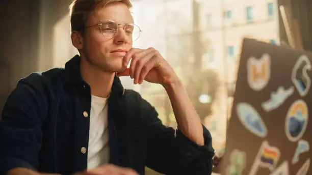 Photo of Focused Male Software Engineer Codding on Laptop Computer and Working With Inspiration in Modern Loft Flat. Man Creating New Mobile Application. Freelancer Doing Remote Work Concept.