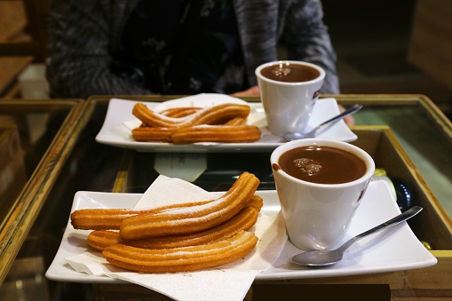 Churros Spanish snack served with hot chocolate. Churros are food items made of fried dough, can be eaten sweet or savory.