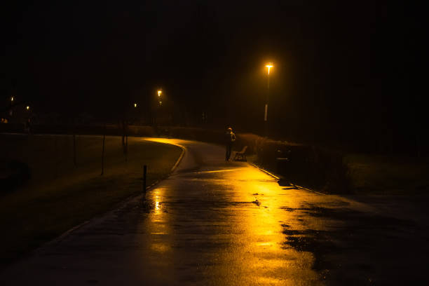 istock street at night, a yellow lantern is on, a man is standing in the distance 1460768607